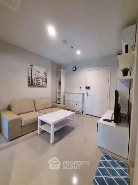 Modern living room with beige sofa, white coffee table, and wall art in a cozy apartment setting.