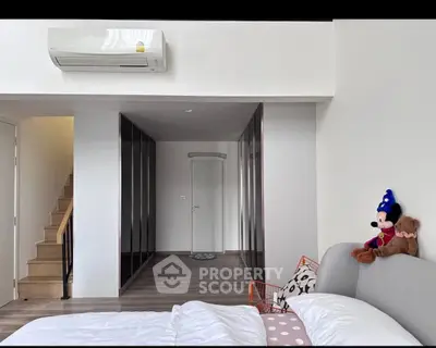 Modern bedroom with stylish decor and air conditioning, featuring a cozy bed and plush toys.