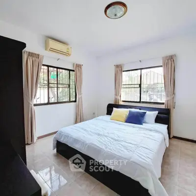 Spacious bedroom with large windows and modern decor in a bright, airy setting.