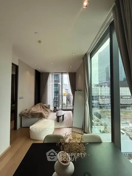 Modern living room with floor-to-ceiling windows and city view, featuring contemporary furniture and elegant decor.
