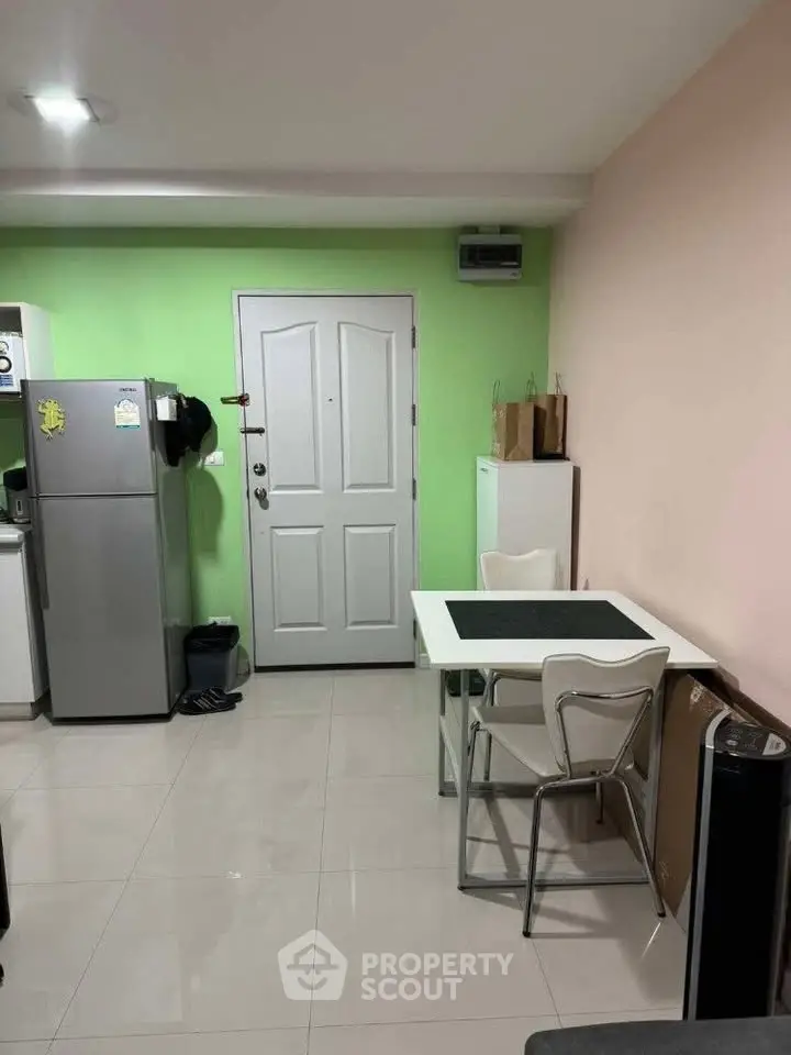 Cozy apartment interior with modern kitchen and dining area, featuring a sleek fridge and stylish decor.