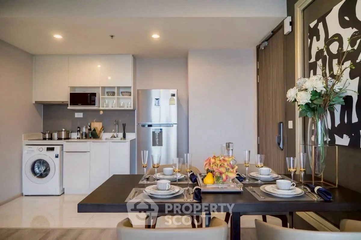 Modern kitchen with dining area, featuring sleek appliances and elegant table setting.