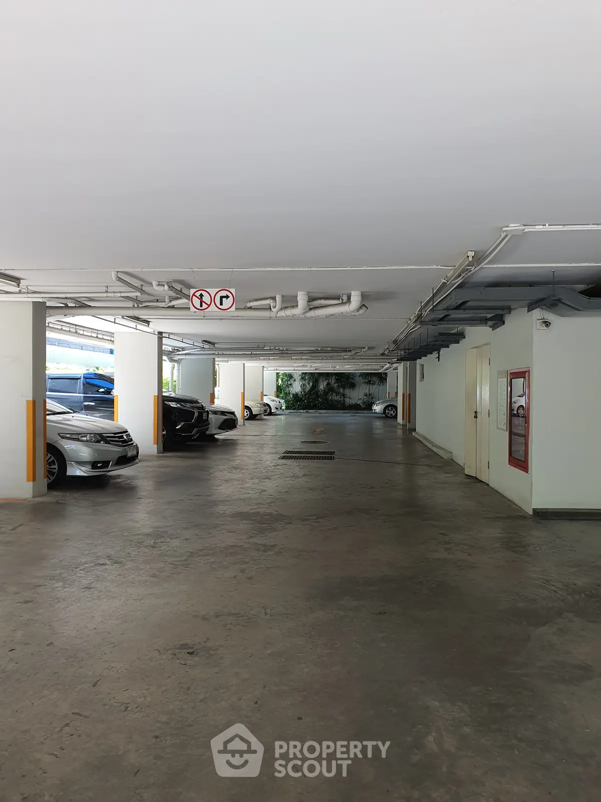 Spacious underground parking area with multiple parked cars and clear signage.