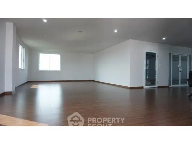 Spacious open-plan living area with wooden flooring and ample natural light.
