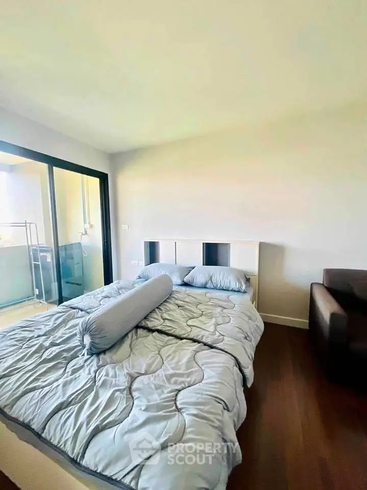 Cozy bedroom with modern decor and balcony access, perfect for relaxation.