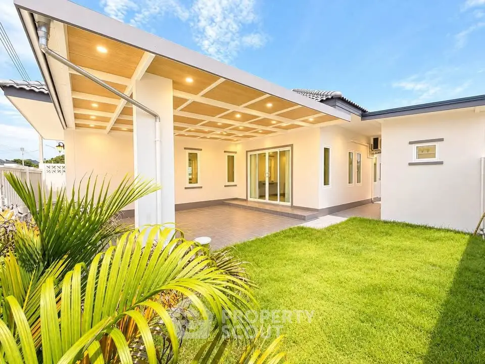 Modern single-story home with spacious patio and lush green lawn under a clear blue sky.