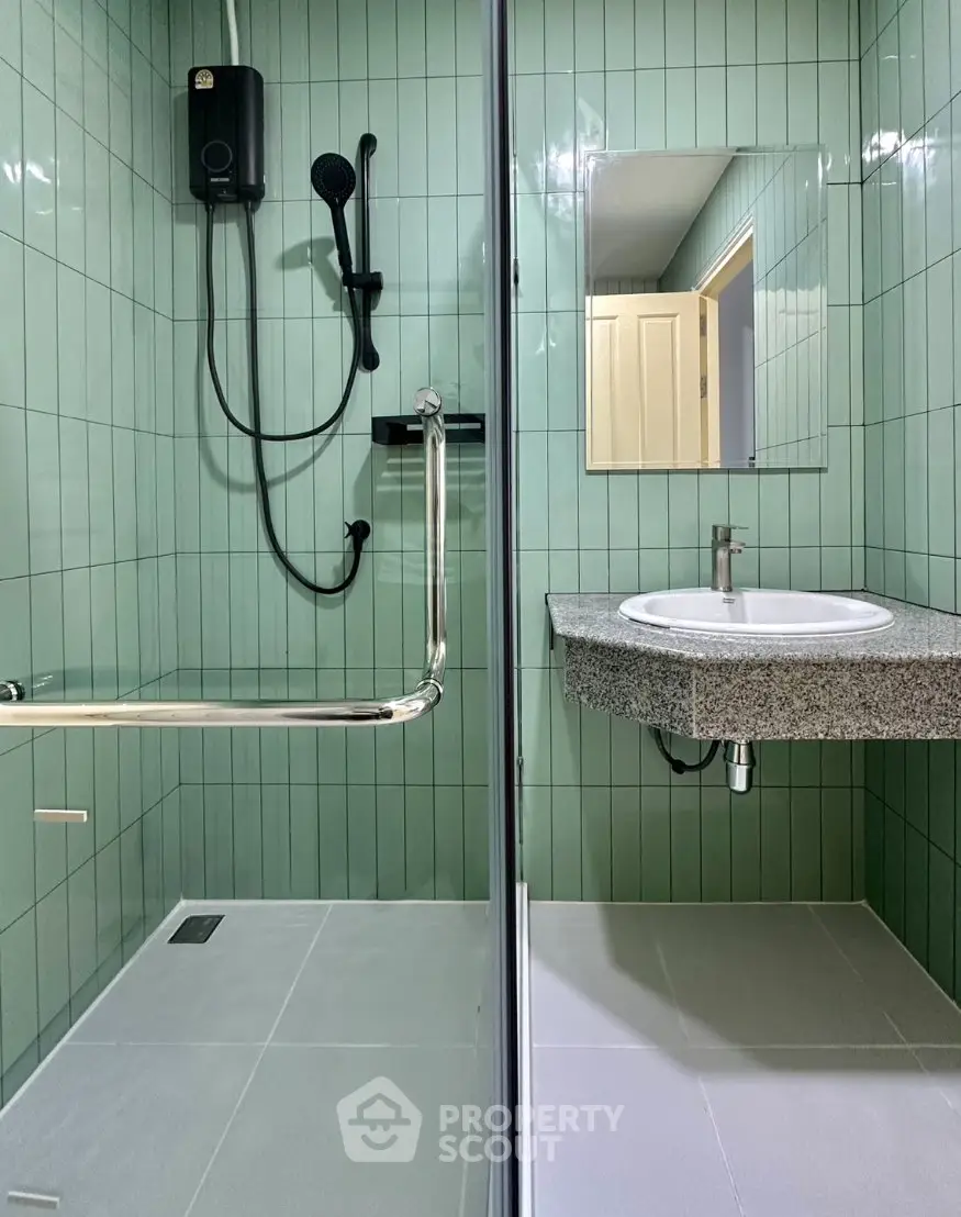 Modern bathroom with sleek green tiles and glass shower enclosure