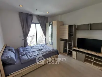 Spacious bedroom with modern furnishings and large window offering city views.