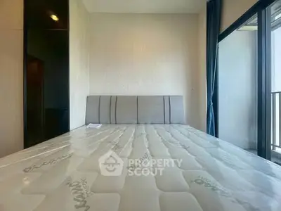 Modern bedroom with large window and balcony access, featuring a stylish headboard and ample natural light.