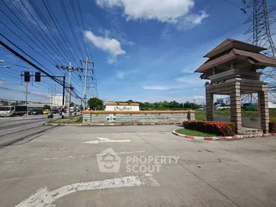 Entrance to a residential community with clear blue skies and lush greenery.