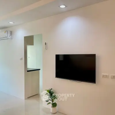 Modern living room with wall-mounted TV and air conditioning unit.
