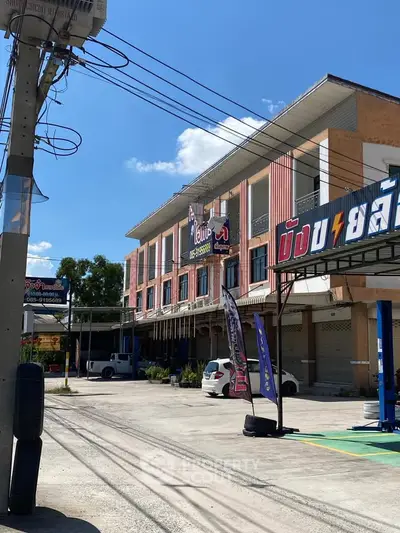 Modern commercial building with parking space and vibrant signage under a clear blue sky.