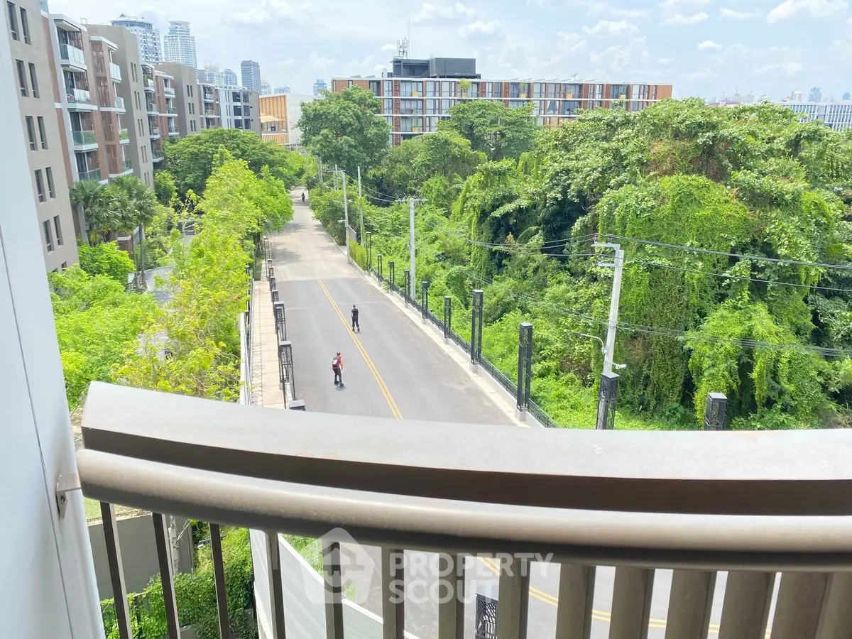 Stunning urban view from a balcony overlooking lush greenery and modern buildings.