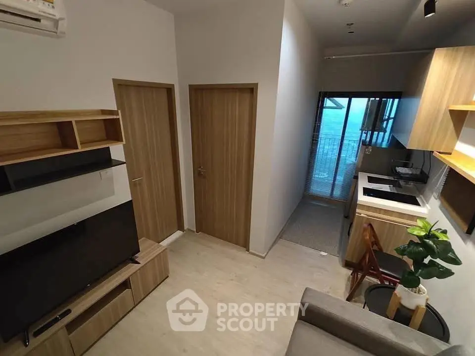 Modern living room with open kitchen and balcony view in stylish apartment.