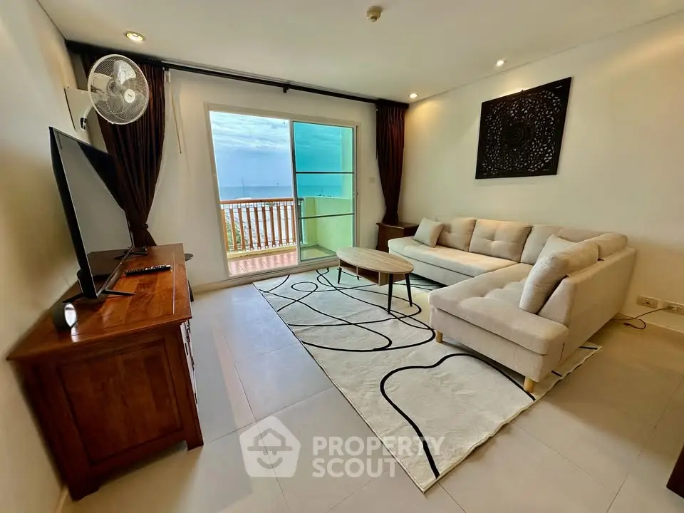 Spacious living room with modern decor and ocean view balcony in luxury apartment.