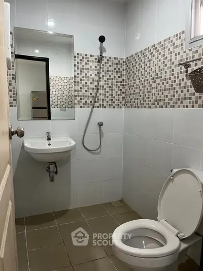 Modern bathroom with shower, sink, and toilet in a tiled interior.