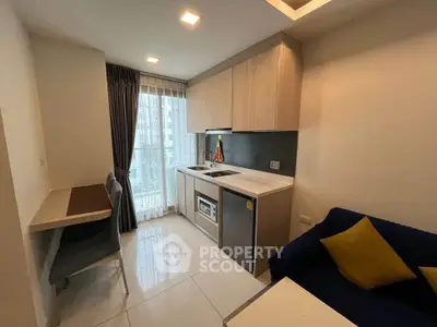 Modern compact kitchen with sleek cabinetry and cozy seating area in a stylish apartment.
