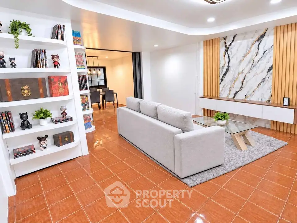 Spacious living room with modern decor and elegant marble accent wall.