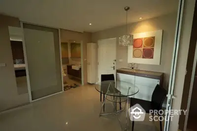 Modern open-plan kitchen with sleek white cabinets and a cozy dining area, complemented by stylish hanging light fixtures and contemporary art.