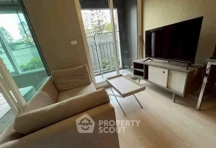 Cozy living room with modern sofa, TV, and balcony access in stylish apartment.