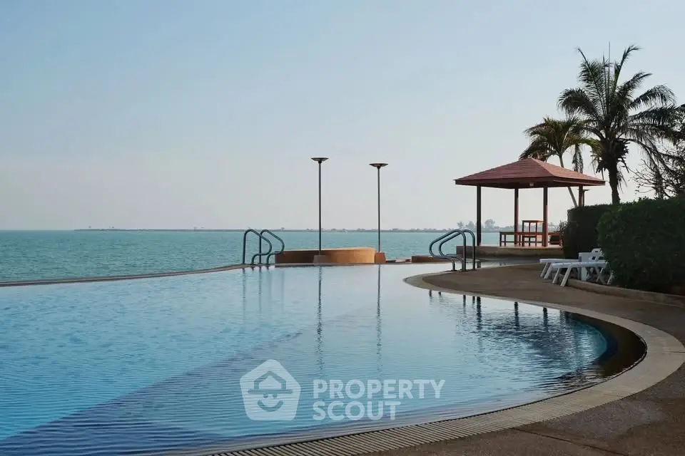 Luxurious waterfront pool with stunning ocean view and palm trees, perfect for relaxation and leisure.