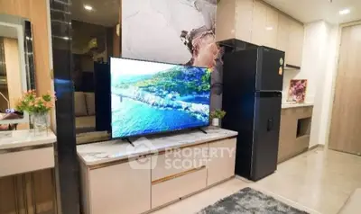 Modern living room with sleek kitchen and large TV, featuring stylish decor and contemporary appliances.