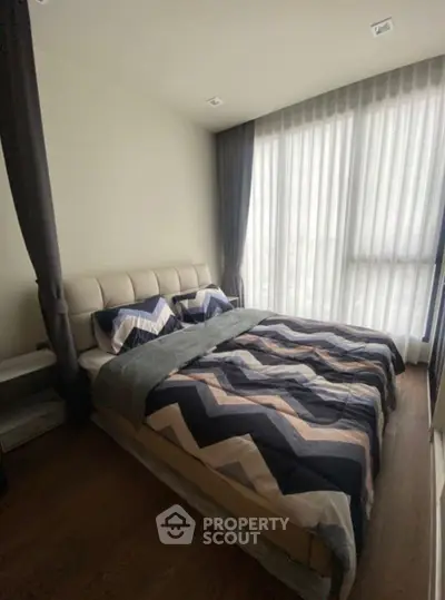 Modern bedroom with large windows and stylish bedding in a cozy apartment.
