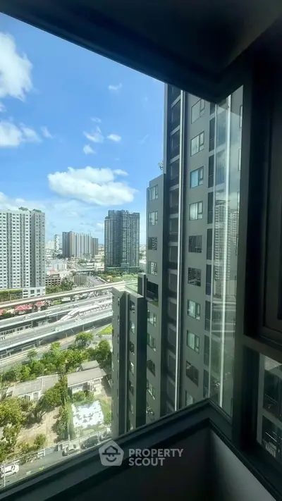 Stunning urban view from high-rise apartment window showcasing city skyline and modern architecture.