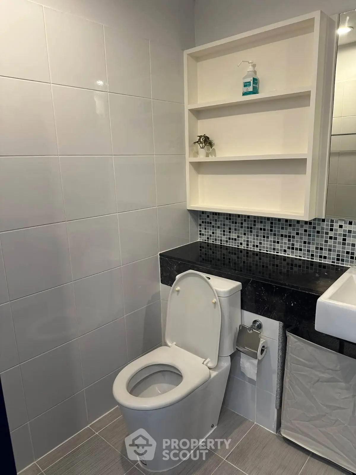 Modern bathroom with sleek design, featuring a toilet, sink, and stylish shelving.