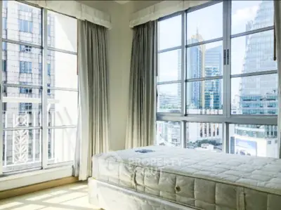 Bright bedroom with large windows offering stunning city views in a modern high-rise building.