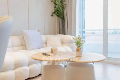 Modern living room with cozy white sofa and stylish coffee tables near large window.