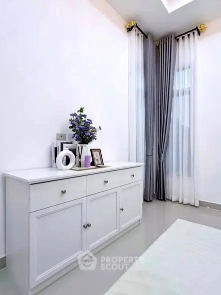 Elegant bedroom corner with white dresser and tall curtains in modern home.