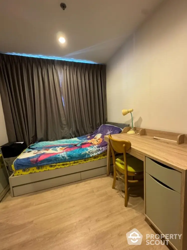 Cozy bedroom with modern desk and stylish bedding in a well-lit apartment.