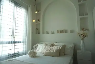 Elegant bedroom with modern decor and natural light, featuring cozy bedding and stylish lighting.