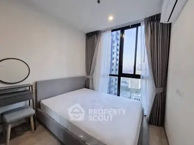Modern bedroom with large window and city view, featuring stylish furniture and neutral decor.