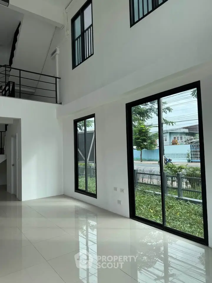 Spacious modern living room with large windows and high ceilings, offering abundant natural light and garden views.