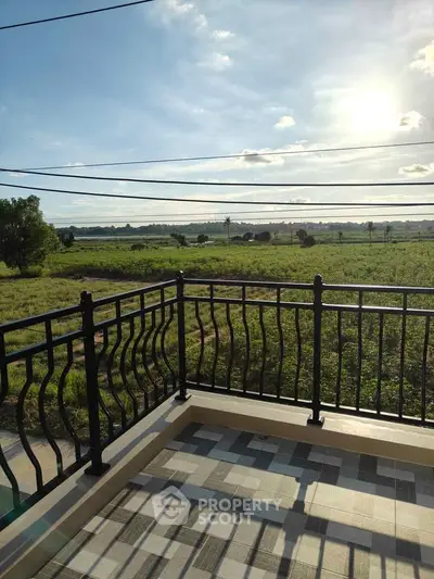 Scenic balcony view overlooking lush green landscape under a bright sky.