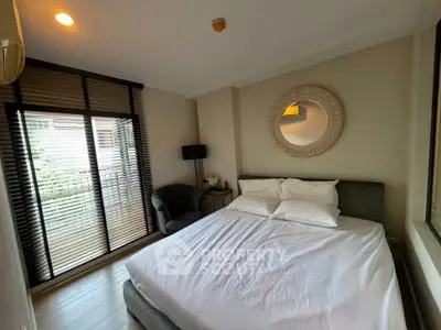 Cozy bedroom with elegant decor and natural light from large window, perfect for relaxation.