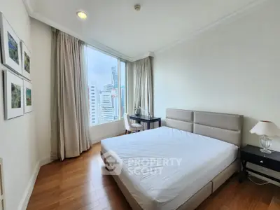 Bright bedroom with city view, featuring a comfortable bed and elegant decor.