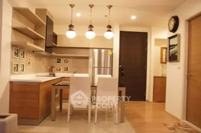 Modern kitchen with stylish lighting and wooden cabinetry in a cozy apartment setting.
