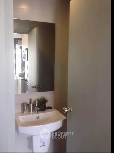 Modern bathroom with sleek sink and mirror in contemporary apartment.