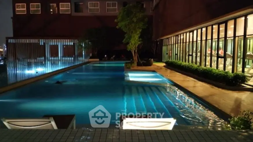Luxurious nighttime poolside view with modern glass-walled gym and ambient lighting.