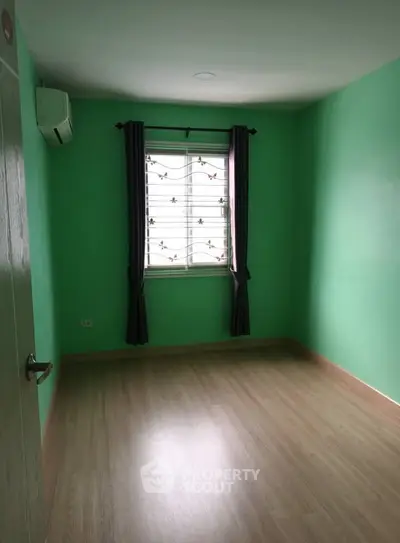 Spacious empty room with vibrant green walls and wooden flooring, perfect for customization.