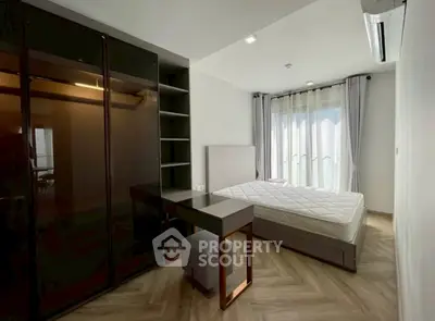 Modern bedroom with sleek wardrobe and stylish desk, featuring natural light and elegant flooring.