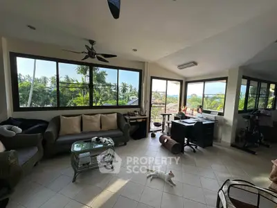 Spacious living room with panoramic windows and lush garden views, perfect for relaxation and productivity.