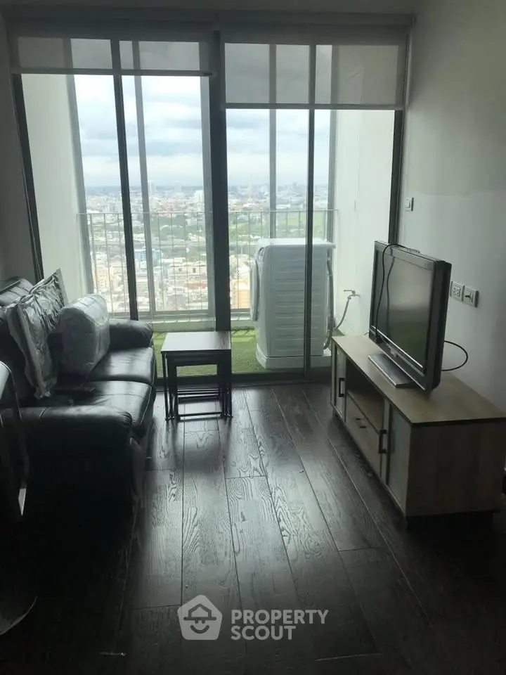 Modern living room with city view, featuring sleek furniture and large windows for natural light.
