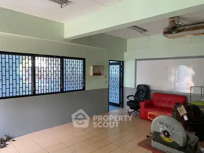 Spacious office room with tiled floor, red sofa, and large windows for natural light.