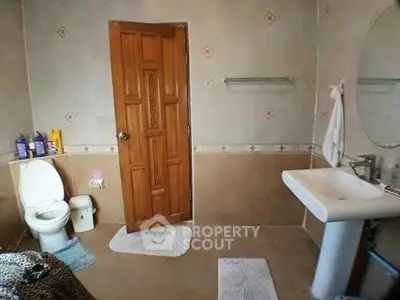 Spacious bathroom with pedestal sink and wooden door