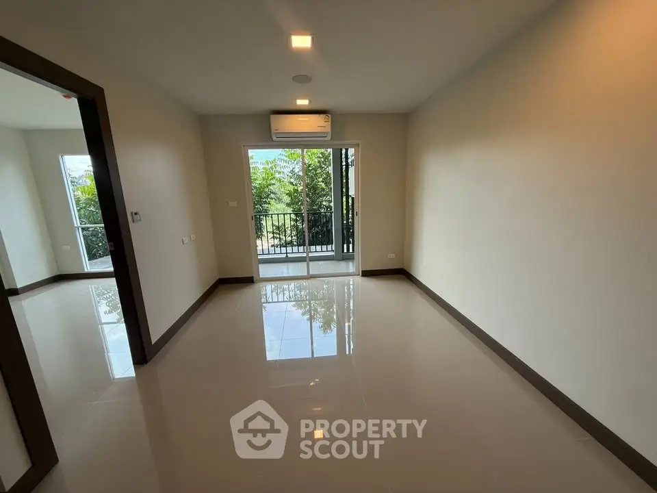 Spacious empty room with glossy floors and balcony view in modern apartment