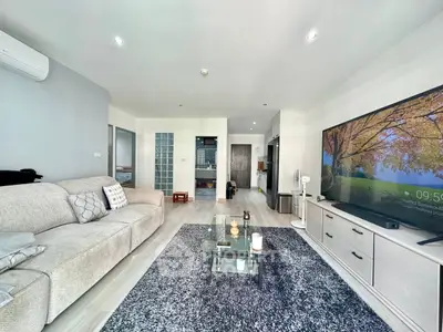 Spacious modern living room with large TV and cozy seating area in a stylish apartment.
